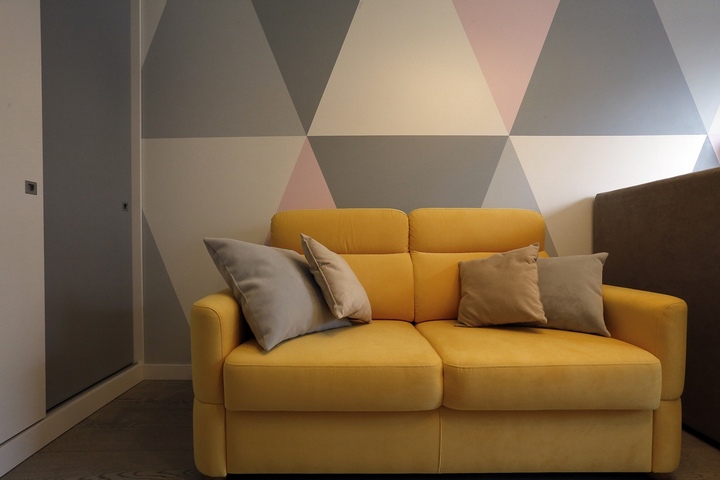 Акцентный желтый диван на фоне сложного рисунка