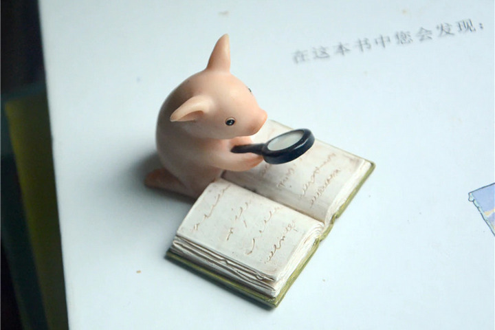 Фигурка свинки, которая читает книгу